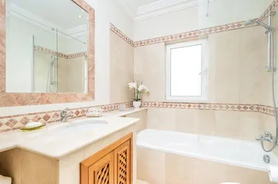 a bathroom with a tub and a sink and a mirror at Villa Sea Renity - Palheiro Village by ALMA Holiday Rentals in Funchal