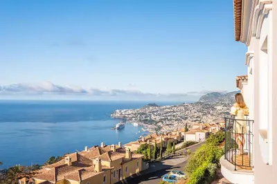 a woman standing on a balcony looking out over the ocean at Villa Sea Renity - Palheiro Village by ALMA Holiday Rentals in Funchal
