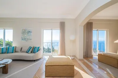 a living room with a couch and some windows at Villa Sea Renity - Palheiro Village by ALMA Holiday Rentals in Funchal