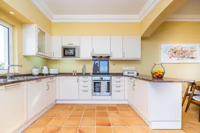 a kitchen with white cabinets and a tile floor at Villa Sea Renity - Palheiro Village by ALMA Holiday Rentals in Funchal