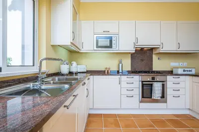 a kitchen with white cabinets and a sink at Villa Sea Renity - Palheiro Village by ALMA Holiday Rentals in Funchal