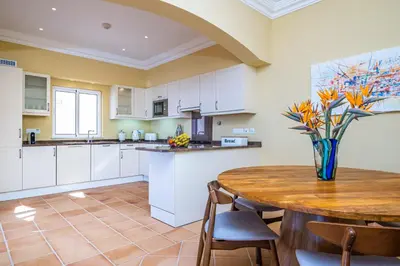 a kitchen with a wooden table with a vase of flowers at Villa Sea Renity - Palheiro Village by ALMA Holiday Rentals in Funchal