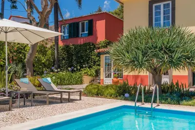 a pool with chairs and an umbrella and a house at Magnificent Funchal Villa Quinta D'alegria 4 Bedrooms Panoramic Sea View in Funchal