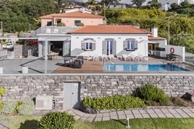a house with a swimming pool and a stone wall at Stunning Funchal Villa 3 Bedrooms Vila Da Portada Panoramic Sea Views in Funchal