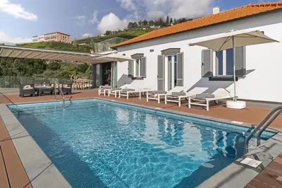 a swimming pool with chairs and a house at Stunning Funchal Villa 3 Bedrooms Vila Da Portada Panoramic Sea Views in Funchal