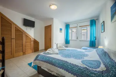 a bedroom with a large bed with blue curtains at Casa Da Paz in Salema