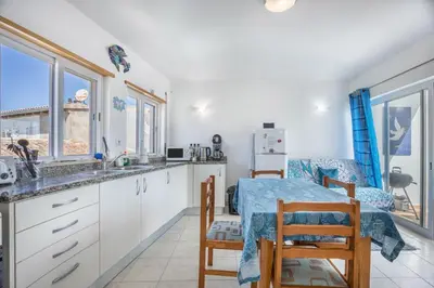 a kitchen with white cabinets and a table and chairs at Casa Da Paz in Salema