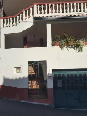 a white building with a green door and a fence at Casa MAR in Madalena do Mar