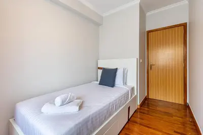 a bedroom with a white bed with two towels on it at Machico City Apt in Machico
