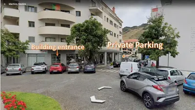 a parking lot with cars parked in front of a building at Machico City Apt in Machico