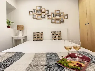 a bedroom with a bed with a tray of food and wine glasses at FX City Life by LovelyStay in Funchal