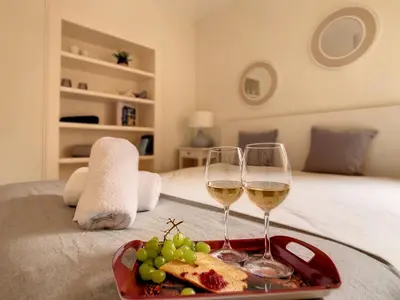 two glasses of white wine and bread and grapes on a bed at FX City Lover by LovelyStay in Funchal