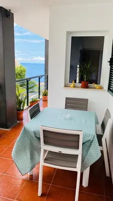 a table and chairs in a room with a balcony at Smarts Apartment da Ajuda in Funchal