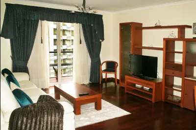 a living room with a white couch and a tv at Smarts Apartment da Ajuda in Funchal
