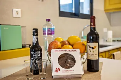 a table with two bottles of wine and a bowl of fruit at Referta Apartamento T2 in Prazeres