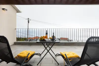 a table with two chairs and bottles of wine on a balcony at Referta Apartamento T1 in Prazeres