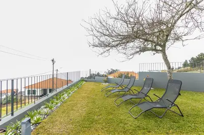a row of chairs sitting in the grass at Referta House in Prazeres