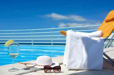 a hat and sunglasses and a glass of wine next to a pool at Sol do Lido 2 in Funchal