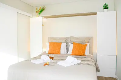a white bed with orange and white pillows at Sol do Lido 2 in Funchal