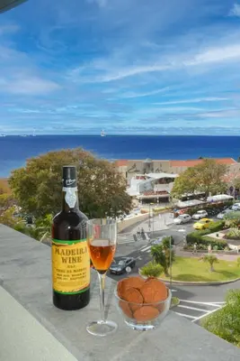 a bottle of wine and a glass on a balcony at Sol do Lido 2 in Funchal