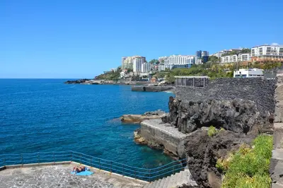 a group of people laying in the water next to the ocean at Sol do Lido 2 in Funchal