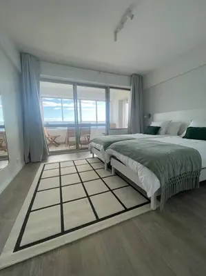 a bedroom with two beds and a large window at top floor avenida arriaga 802 in Funchal