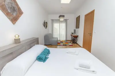 a bedroom with a white bed and a chair at B81 - Casa do Outeiro Westcoast Home in Vila do Bispo