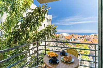 a table with food on a balcony with a view of a city at Yellow Rose by AH in Funchal