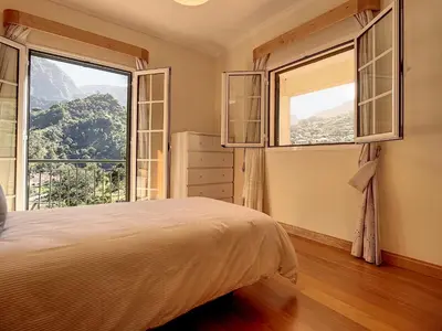 a bedroom with a bed and two large windows at Mountain View Villa by Atlantic Holiday in São Vicente