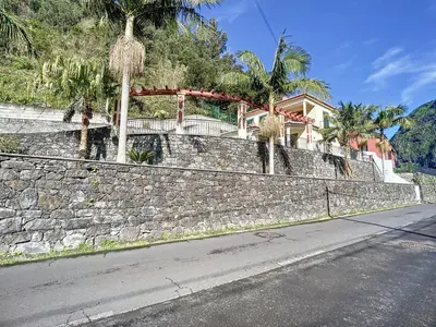 a house on a stone wall next to a street at Mountain View Villa by Atlantic Holiday in São Vicente