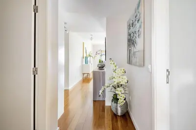 a hallway with white walls and a table with flowers at Luxury poolside view apartment in Funchal