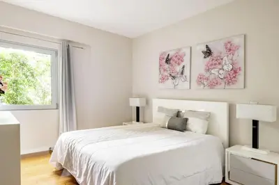 a white bedroom with a large bed and a window at Luxury poolside view apartment in Funchal