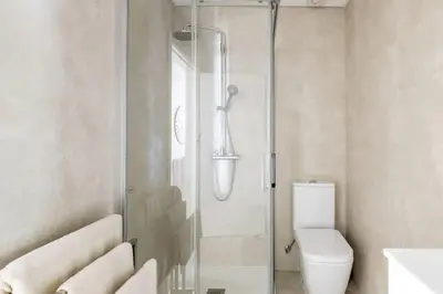 a white bathroom with a shower and a toilet at Luxury poolside view apartment in Funchal