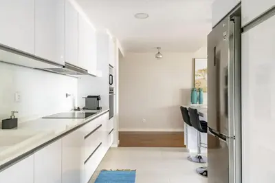 a kitchen with white cabinets and a stainless steel refrigerator at Luxury poolside view apartment in Funchal