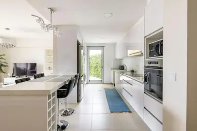 a kitchen with white appliances and a blue rug at Luxury poolside view apartment in Funchal