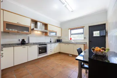 a kitchen with white cabinets and a table with a bowl of fruit at The Green Sheep Sagres in Sagres
