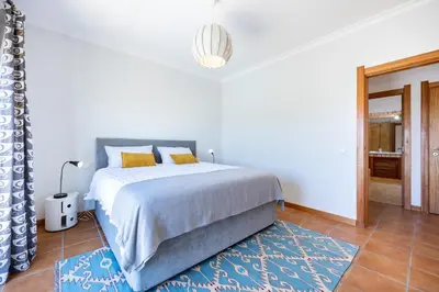 a white bedroom with a bed and a blue rug at The Green Sheep Sagres in Sagres