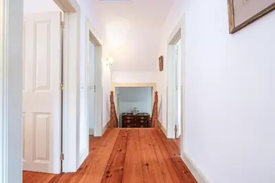 a hallway with wooden floors and white walls and white doors at Casa dos Castanheiros in Camacha