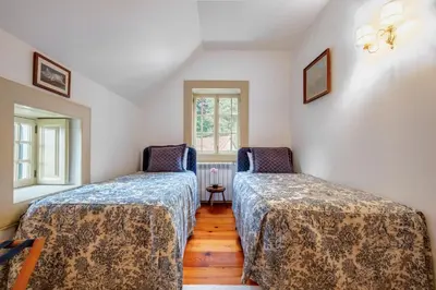 two beds in a room with white walls and wooden floors at Casa dos Castanheiros in Camacha