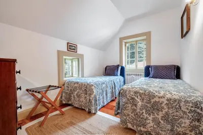 a bedroom with two beds and two windows at Casa dos Castanheiros in Camacha