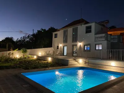 a swimming pool in front of a house at night at Tranquilidade in Estreito da Calheta