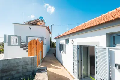 a white house with a gate and a fence at Tranquilidade in Estreito da Calheta