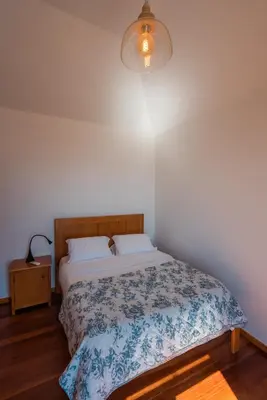 a bedroom with a bed with a blue and white blanket at Tranquilidade in Estreito da Calheta