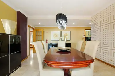 a dining room with a wooden table and white chairs at Apartamento Caires in Funchal