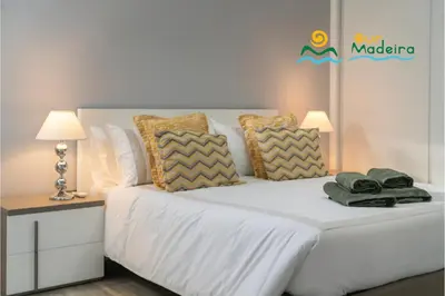 a bedroom with a bed with white sheets and pillows at OurMadeira - OceanScape in Madalena do Mar