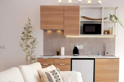 a kitchen with wooden cabinets and a white couch at Vi Naturae Glamping in Fajã da Ovelha