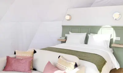 a bedroom with a large bed with pink pillows at Vi Naturae Glamping in Fajã da Ovelha