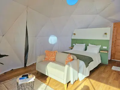 a bedroom with a bed and a couch in a tent at Vi Naturae Glamping in Fajã da Ovelha