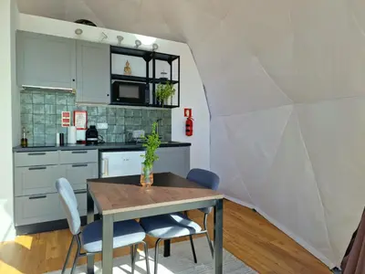 a kitchen and dining room with a table and chairs at Vi Naturae Glamping in Fajã da Ovelha