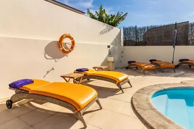 a patio with orange cushioned chairs and a swimming pool at Villa Retiro in Canhas